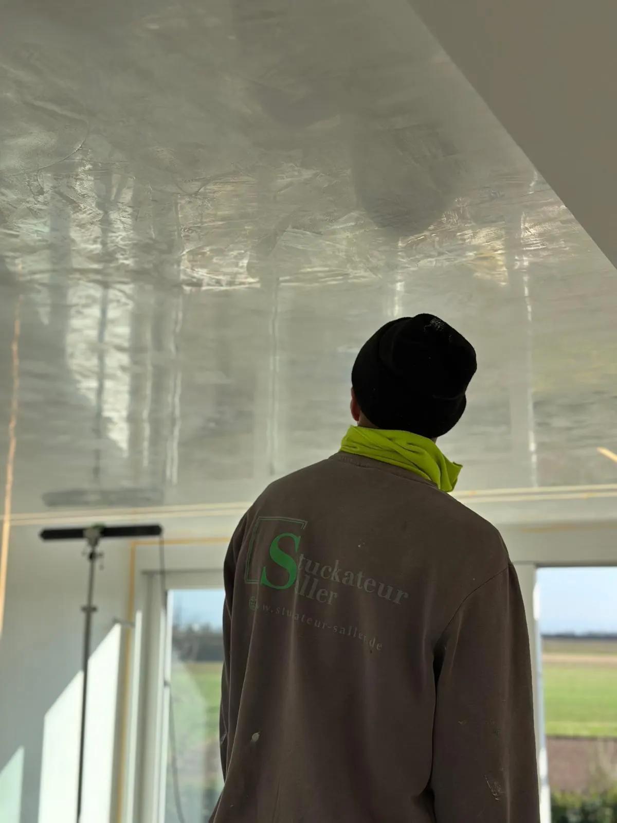 Hochglänzend gespachtelte Decke, Mitarbeiter von Stuckateur Saller schaut nach oben