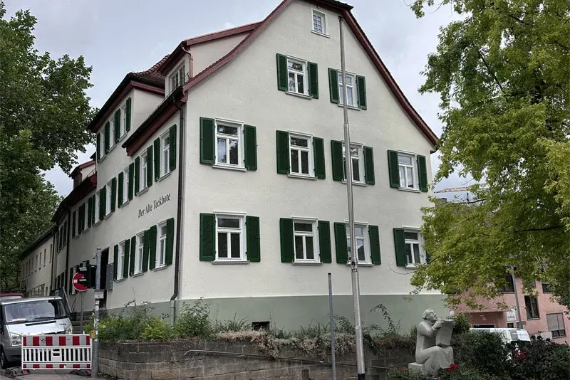 Dreigeschossiger Altbau mit weißer Fassade und grünen Läden