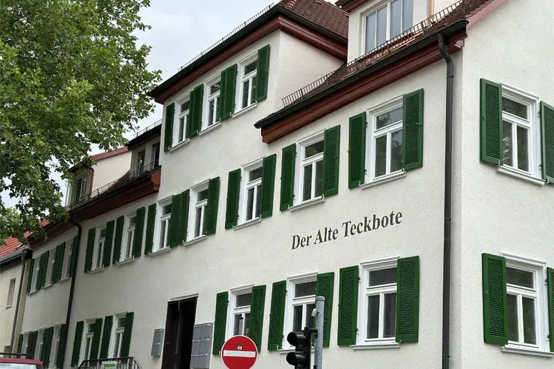 Fassade mit grünen Fensterläden und Schriftzug