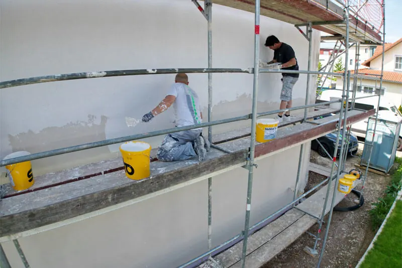 Mitarbeiter verputzt die gedämmte Fassade